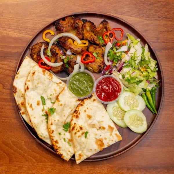 Desi Bistro's Indian platter with grilled chicken, naan, salad, and two dipping sauces.
