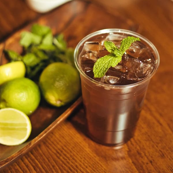 Iced Desi Bistro drink with mint and limes on a wooden tray.