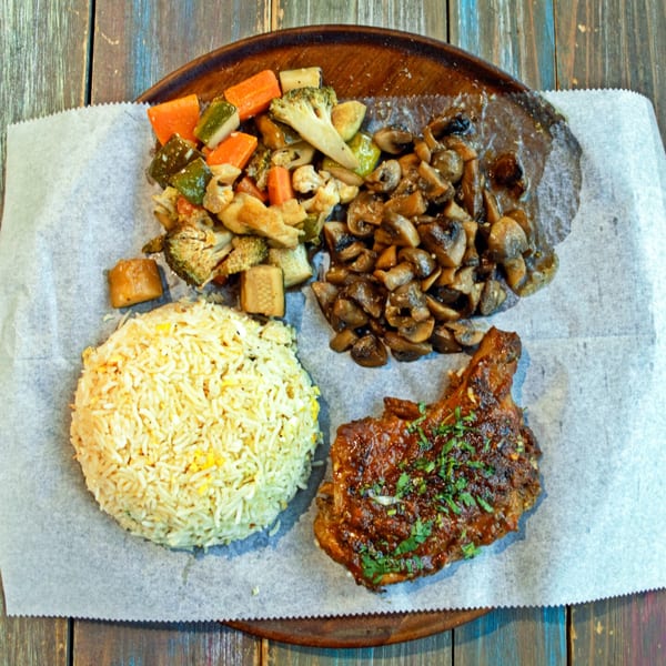 Desi Bistro's Indian dish with rice, grilled chicken, sauteed mushrooms, and mixed vegetables on a wooden platter.