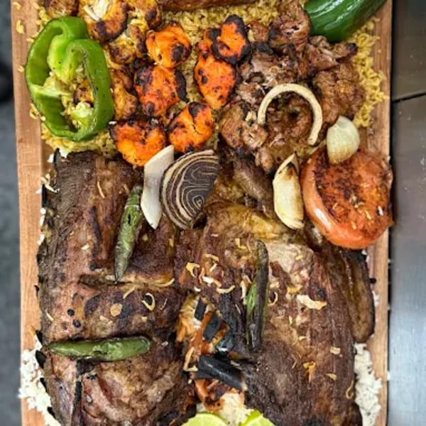 A large platter of grilled Indian meats, fish, and vegetables on a bed of rice.